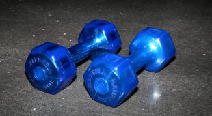 Front view of a pair of blue Hampton Jelly-Bells lying on a gym floor.