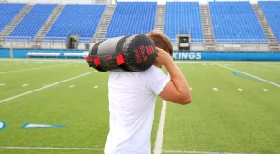 Athlete on a football field using the Hampton Compound Sandbag