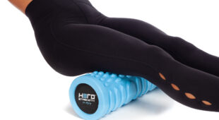 female athlete rolling hamstrings on a blue foam roller