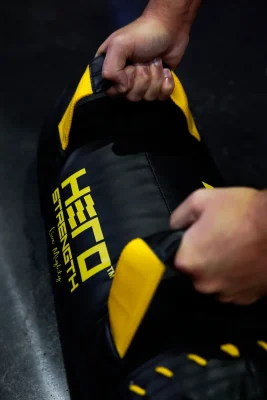 athlete gripping a black and yellow weighted bag