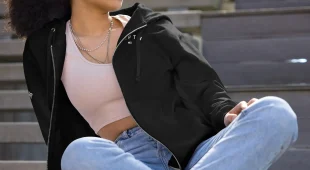 female sitting outside modeling a black hampton zip up hoodie with logo on chest